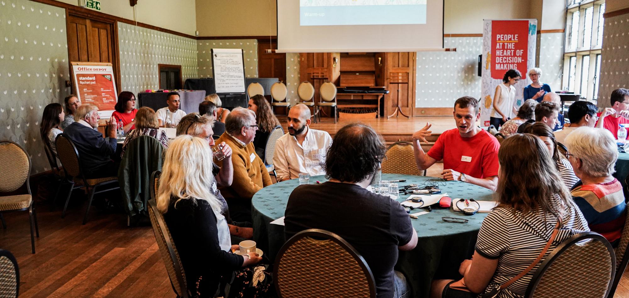 Image of the Wales Citizens Assembly, with people in discussion at tables