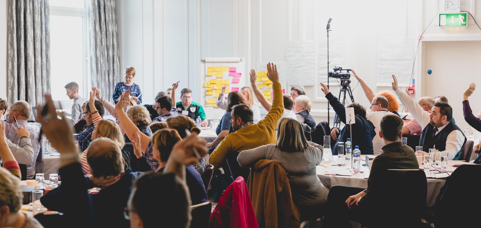 People in a room with hands raised.