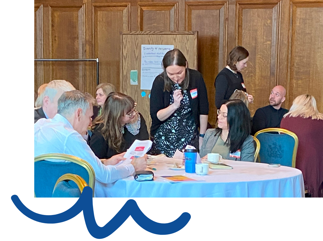 People standing and sitting around tables during a workshop.