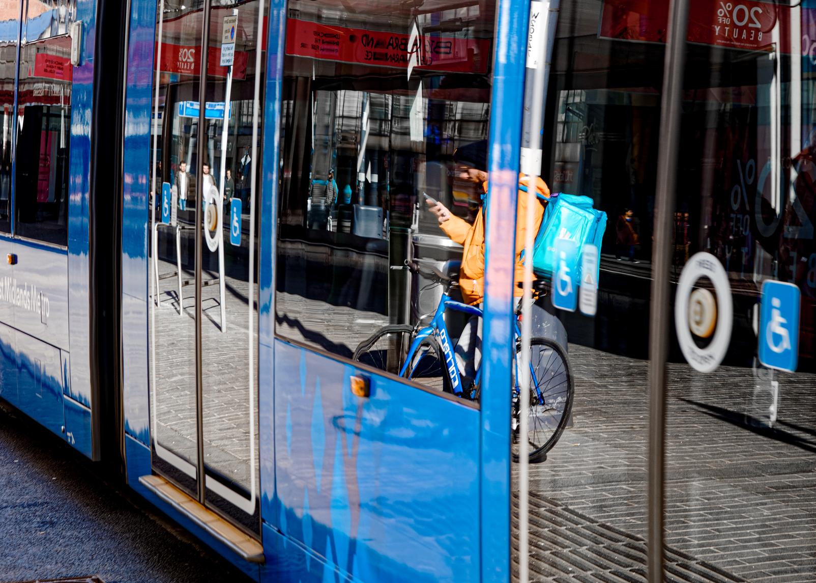 A reflection of a cyclist in a West Midlands tram