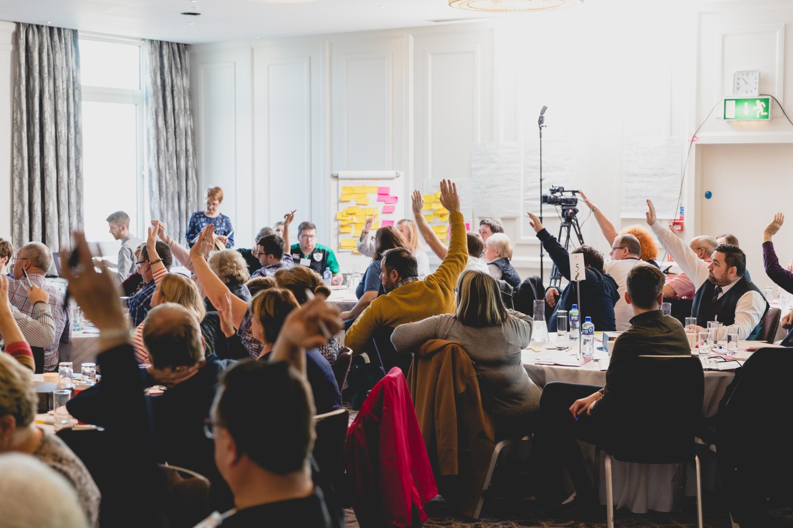 NI Citizens' Assembly - assembly members raising their arms in response to a question