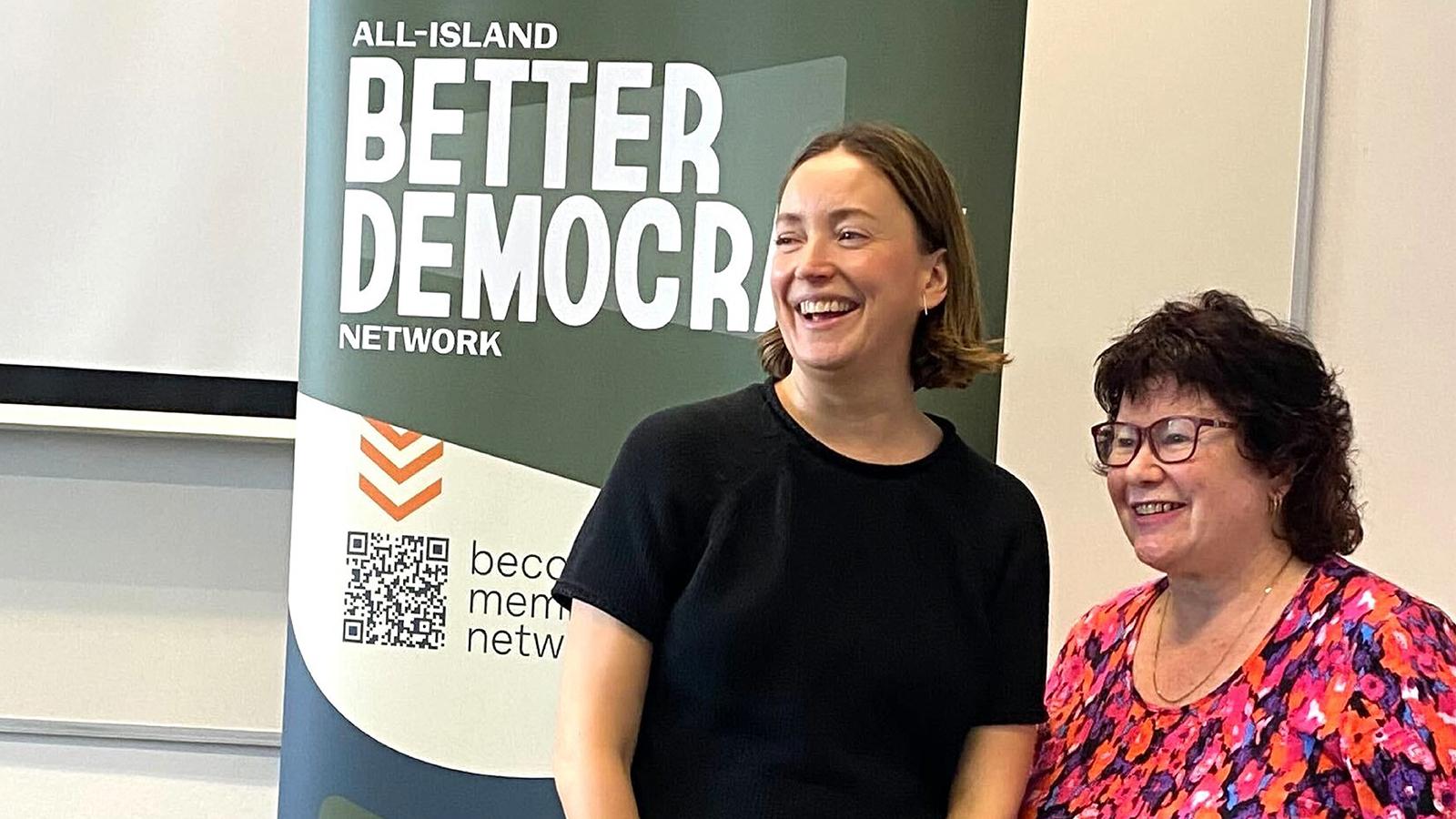Rebekah McCabe and Nivek Thompson in front of a banner.