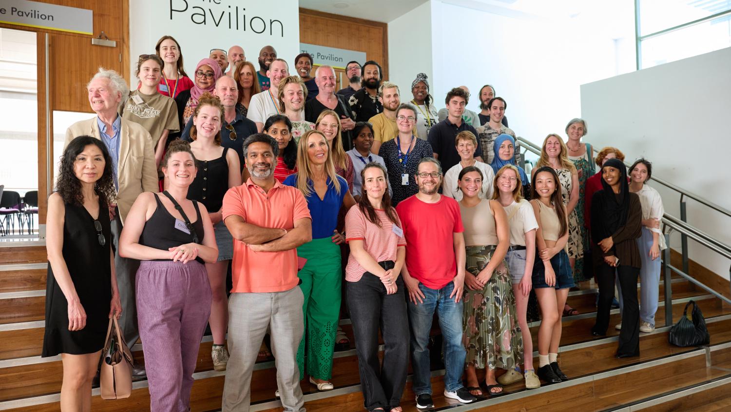 Image of a group of people stood smiling together on a set of stairs