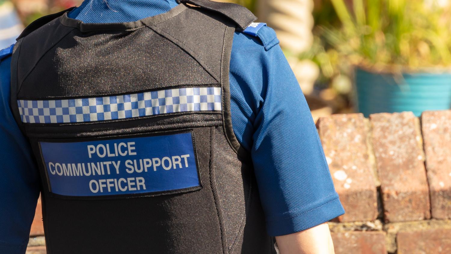 Back of a police officer. Vest reads "POLICE COMMUNITY SUPPORT OFFICER"