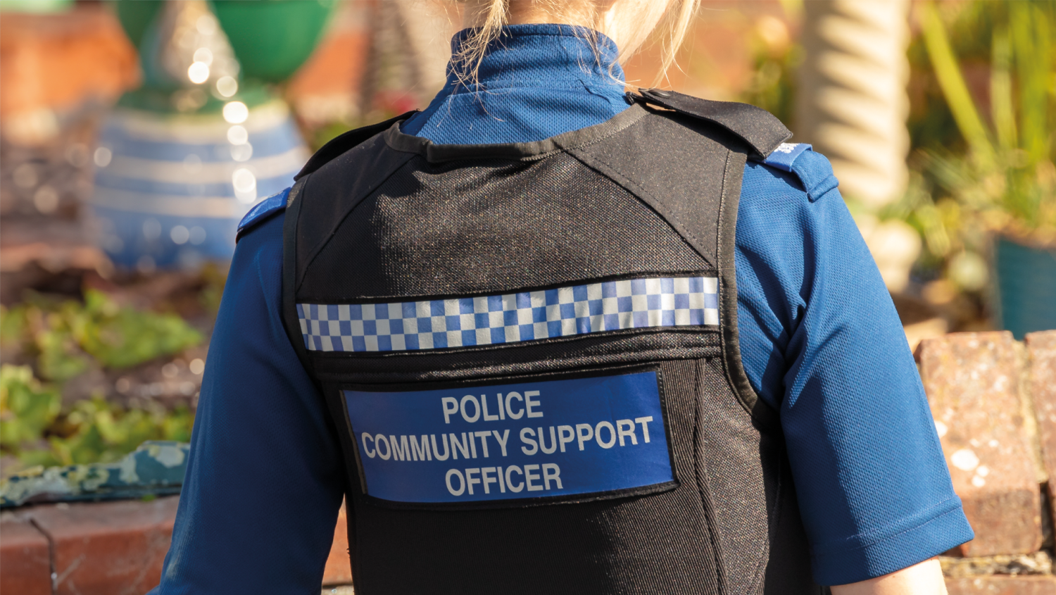 Back of a police officer. Vest reads "POLICE COMMUNITY SUPPORT OFFICER"
