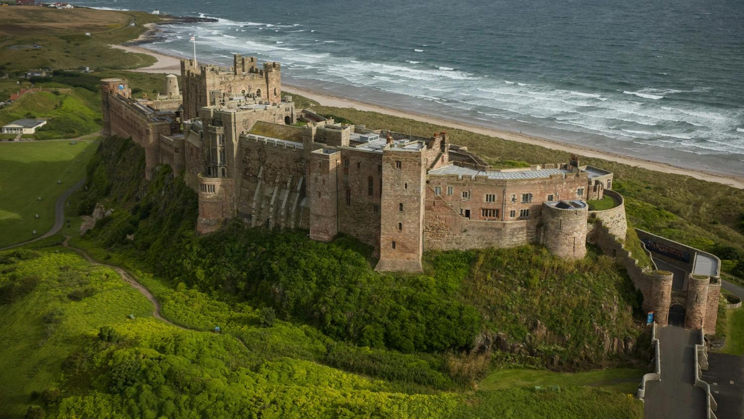 Bambrough Castle in Northumberland against a cloudy grey sky and the sea