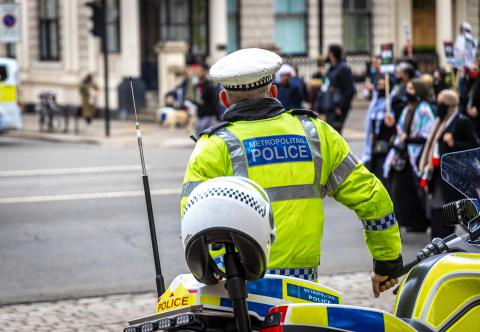 A metropolitcan police officer overlooks protestors as they walk by